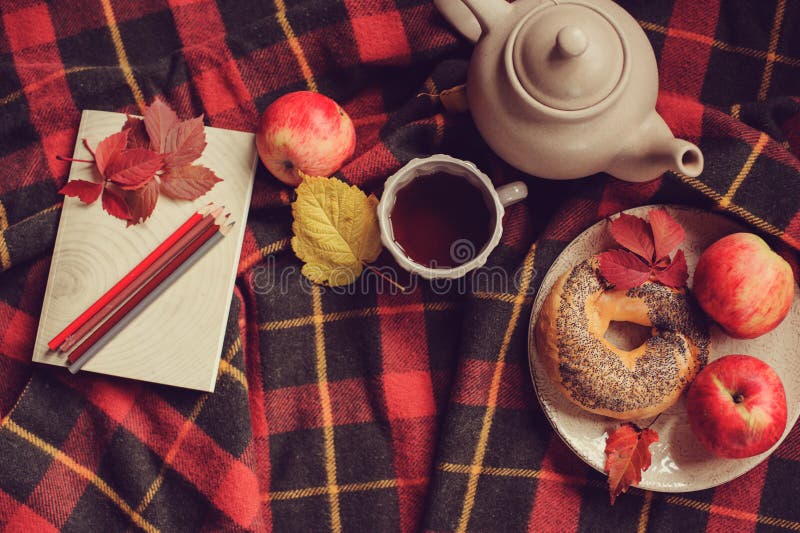 Top view of cozy autumn morning at home. Breakfast with pot of tea and bagel with apples
