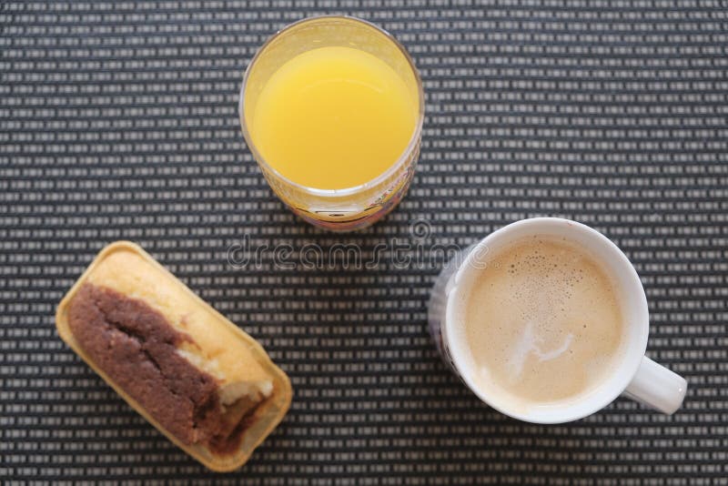 Top view of a cup of coffee and a glass of juice with a slice of cake on a table