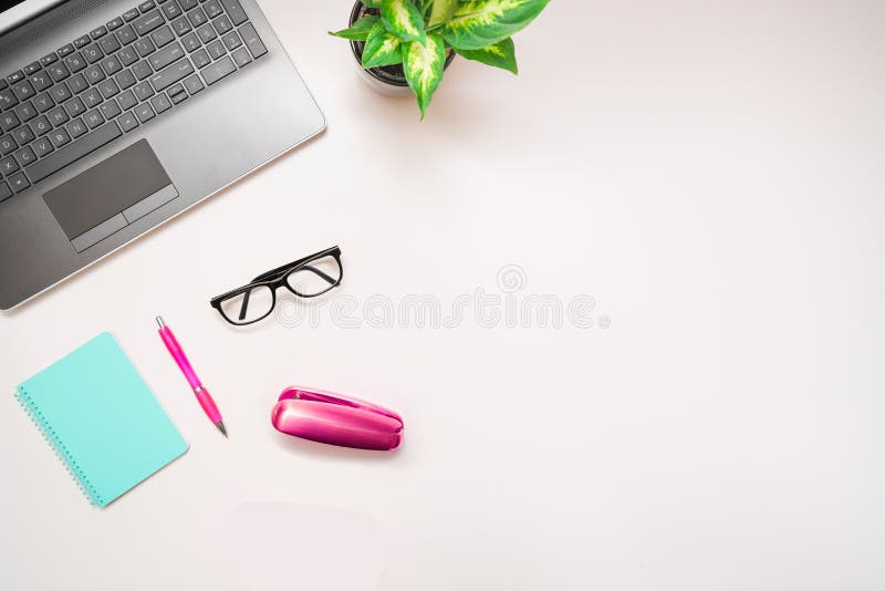 Top view of desk with a laptop, a plant, glasses and supplies. White background. Copy space. Banner background.