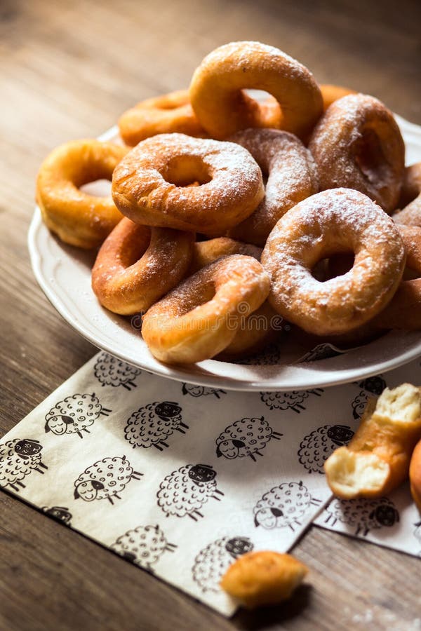 Top view detail on a bunch of fresh homemade donuts (doughnuts) on a white plate, with sugar bowl, rolling pin stock photo Top view detail on a bunch of fresh homemade donuts (doughnuts) on a white plate, with sugar bowl, rolling pin stock photo