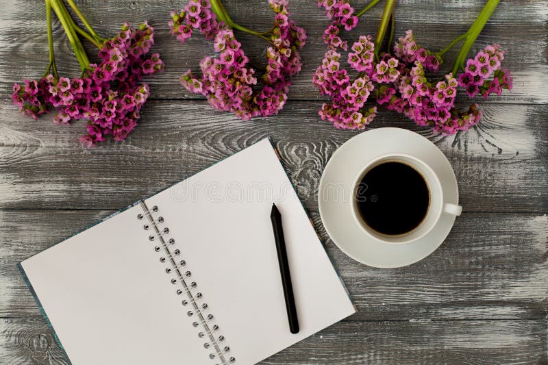 Top view of a diary or notebook, pencil and coffee and a purple flower on a gray wooden table. Flat design.