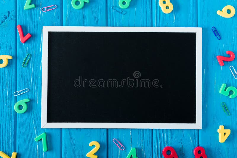 top view of empty blackboard colorful numbers and paper clips on blue wooden