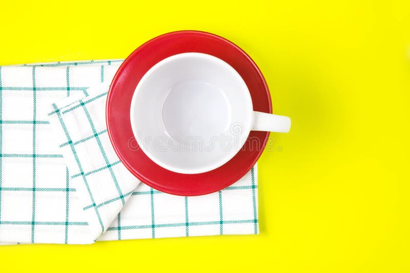 top view of empty white coffee or tea cup with red dish and towel on vibrant color background