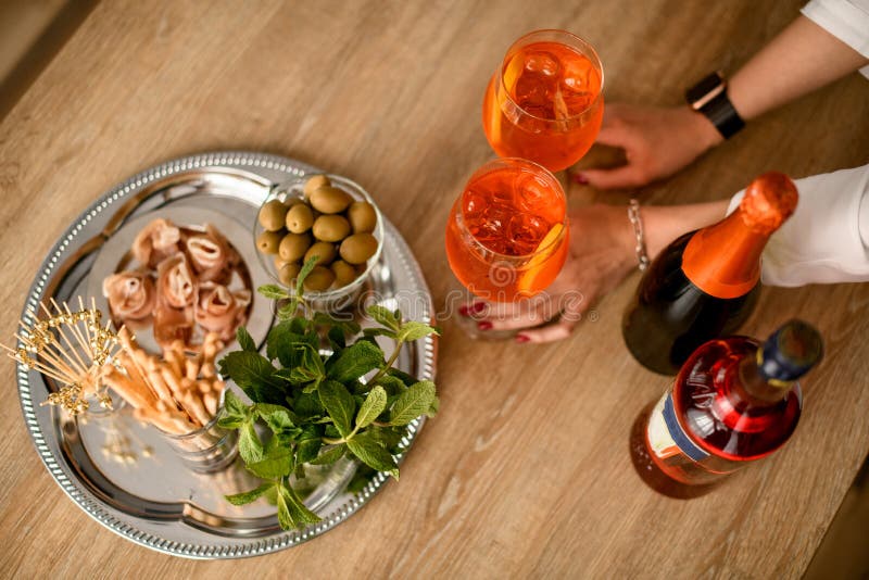 Top view of female hands hold two glasses of cold bright orange drink which stands on the table royalty free stock photos