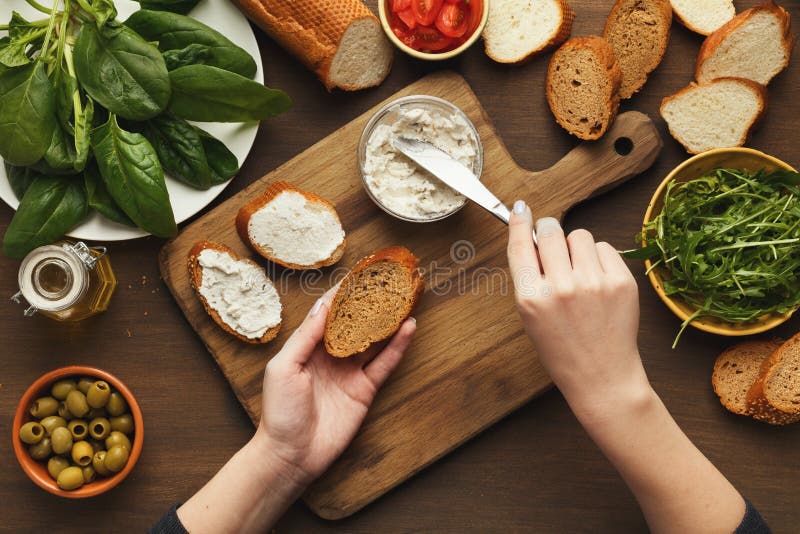 Top view on female hands making vegetable bruschettas