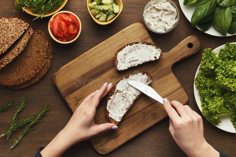 Top view on female hands making vegetable bruschettas