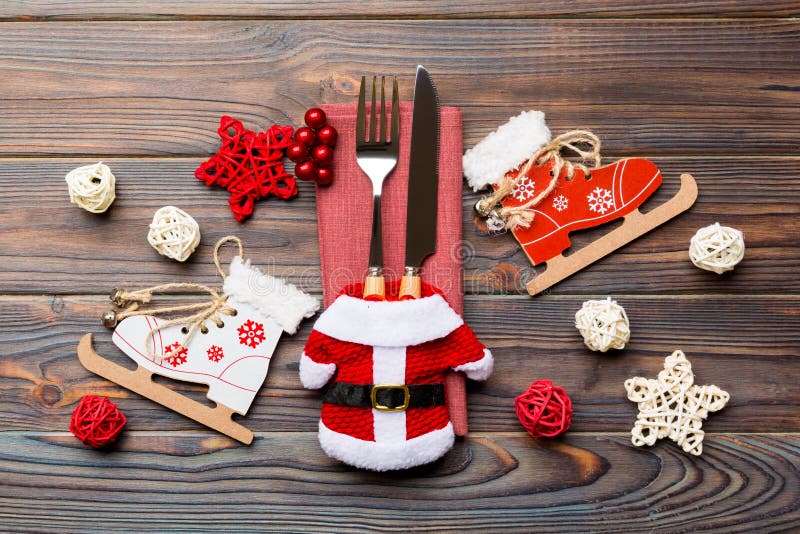 Top view of fork and knife on napkin on wooden background. Different christmas decorations and toys. Close up of New Year dinner