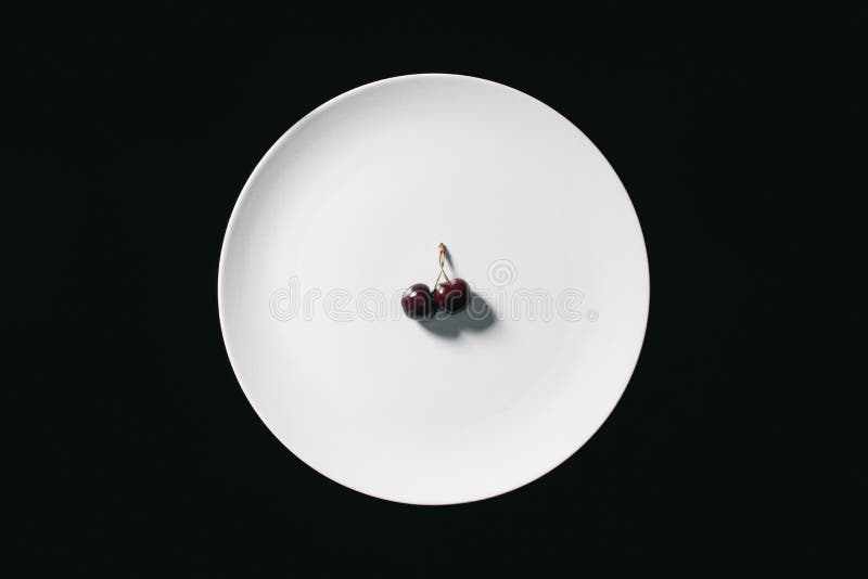 top view of fresh ripe sweet red cherries on round white plate