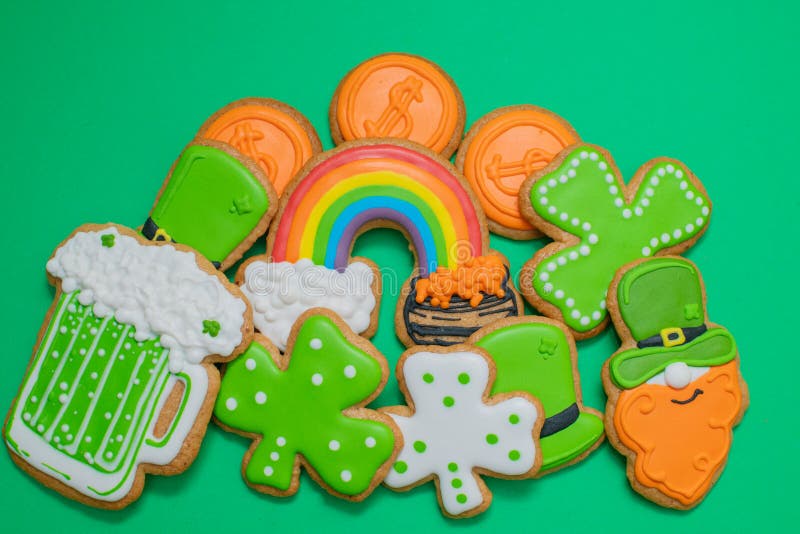 Top view of freshly baked St. Patricks Day decorated sugar cookies on green background. Homemade cookies with shamrock. Rainbow, leprechaun and pot of gold royalty free stock photography