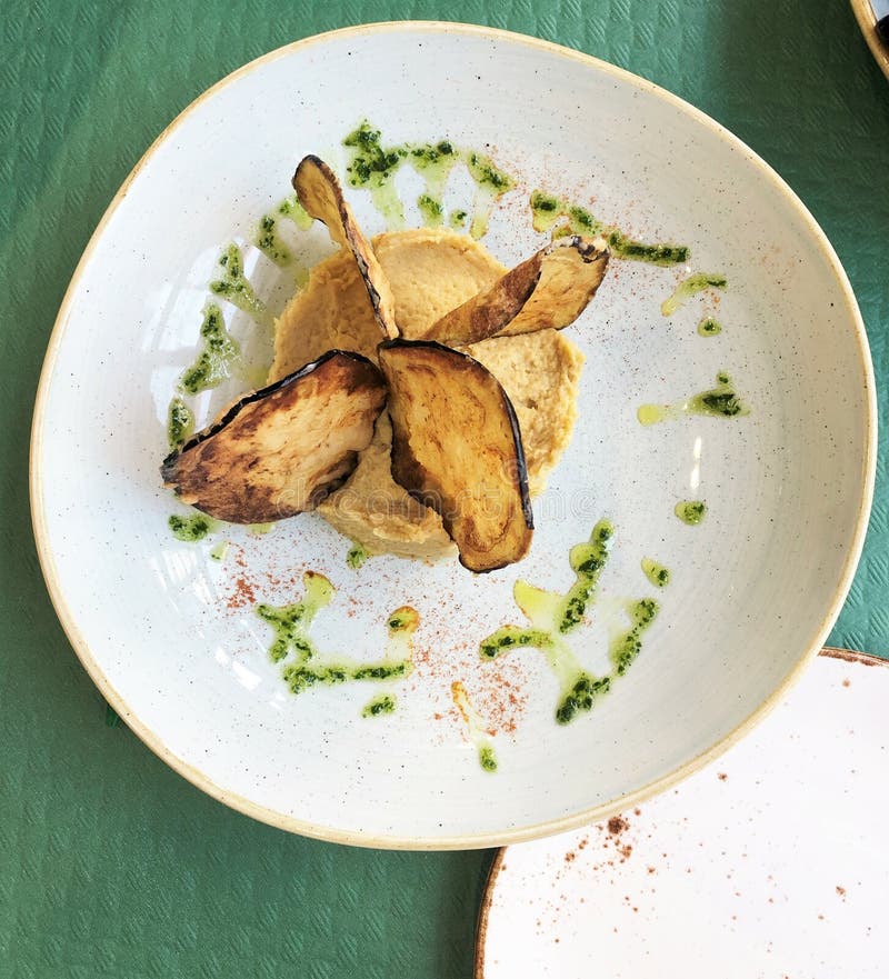 Top View of Fried Eggplant Chips on Mashed Potato with Herbs on a White