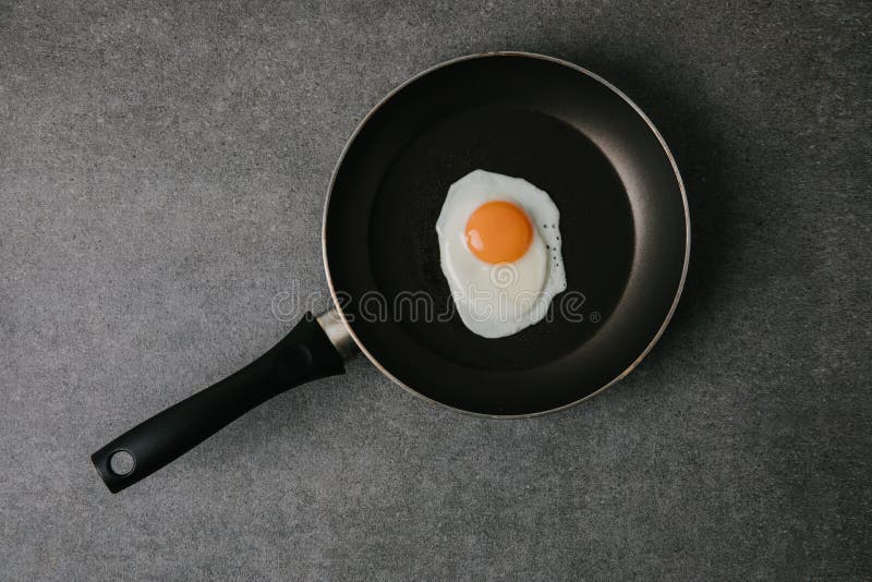 top view of frying pan with tasty fried egg on grey royalty free stock images