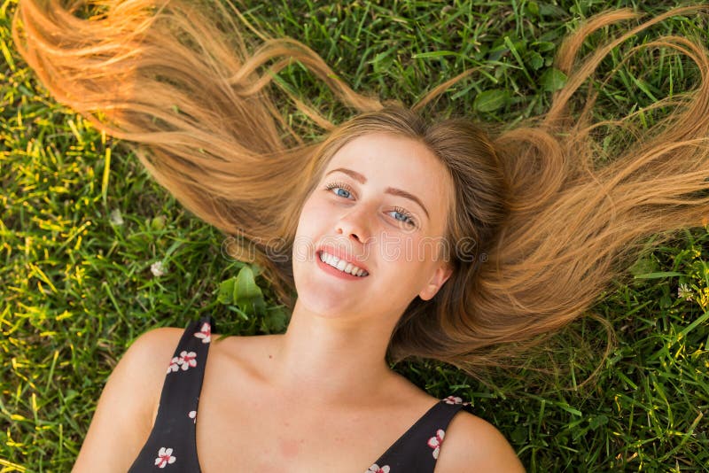 Top view of a happy relaxed woman lying on the green grass and smiling. royalty free stock photography Top view of a happy relaxed woman lying on the green grass and smiling. royalty free stock photography