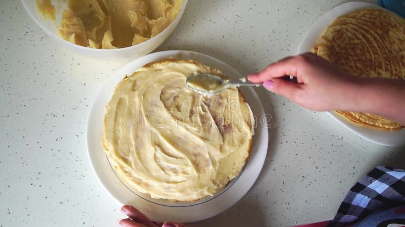 Top view of how female hands smear a cream cake. Girl smears cake with cream