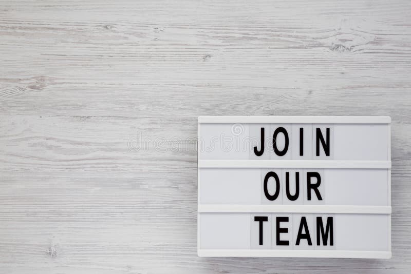 Top view, `Join our team` words on a modern board on a white wooden surface. Overhead, from above, flat lay. Copy space stock photos