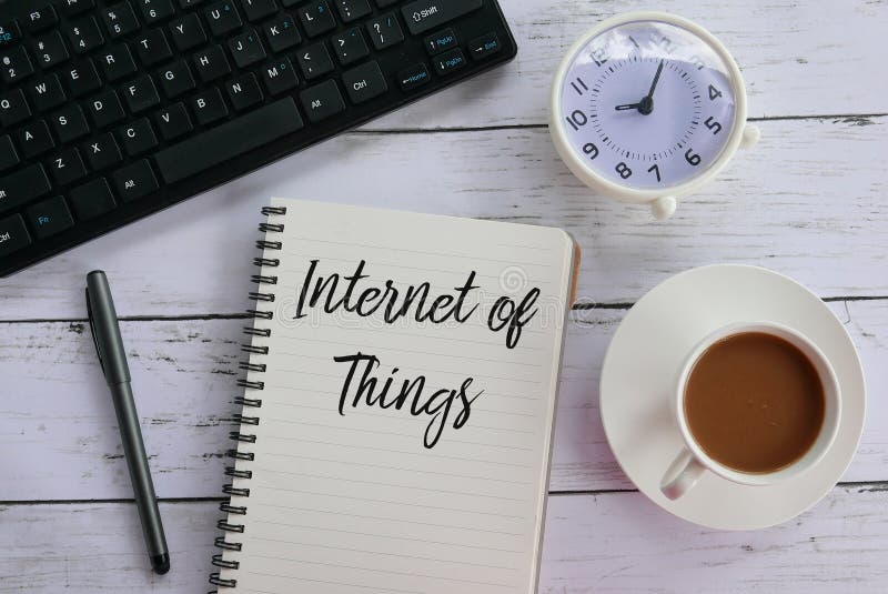 Top view of keyboard,clock,coffee,pen and notebook written with Internet of Things. stock images
