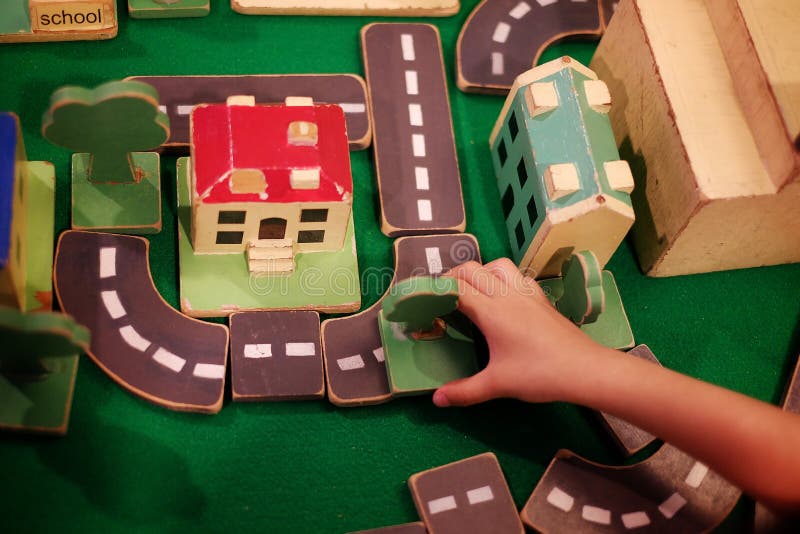 Top view of a kid building a city from wooden blocks with trees, roads and buildings stock photo Top view of a kid building a city from wooden blocks with trees, roads and buildings stock photo