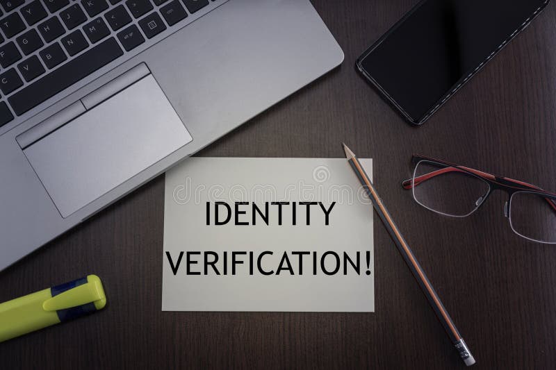 Top view of laptop, phone, glasses and pencil with card with inscription identity verification stock photos