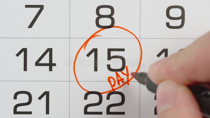 TOP VIEW: Marking a pay day in a calendar by red pen - Macro shot