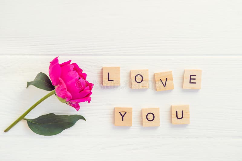 Top view Message I love you spelled in wooden blocks with purple pink peony flower on white wooden table. Love, Valentines day bac. Delicate, backdrop.