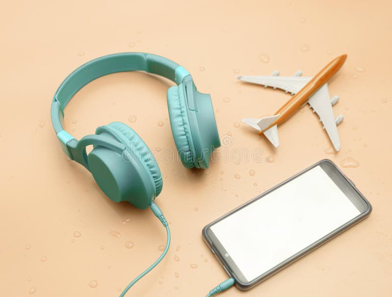Top view, mint music headphones in water drops, with airplane travel concept, copy space. Headphones on a pastel beige background stock image