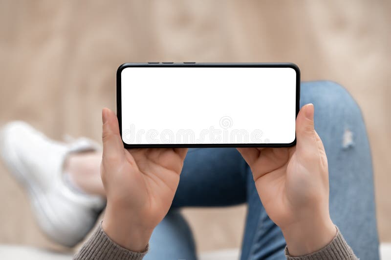 Top view mockup image of woman holding mobile phone horizontally with blank white screen. woman using cellphone horizontal with stock image
