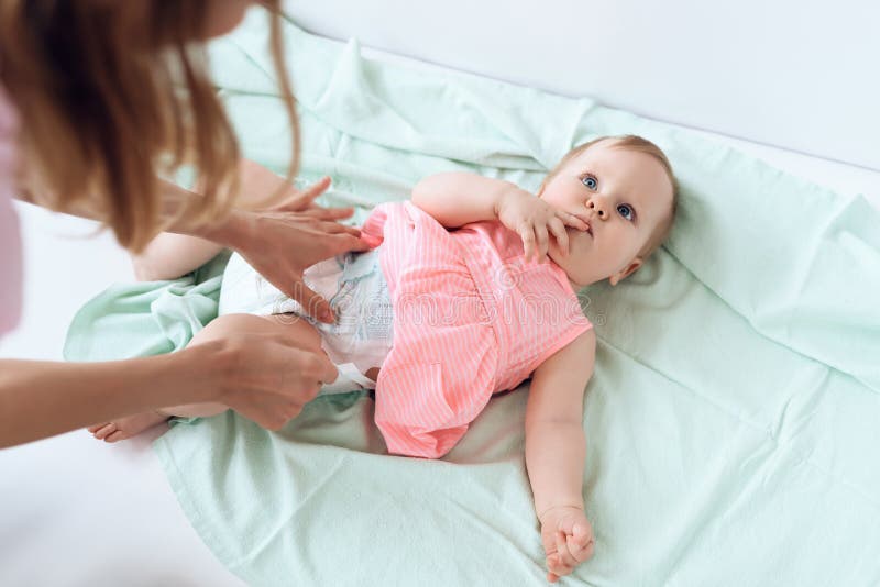 Top view. Mom giving baby diaper change at home. Newborn, motherhood concept.