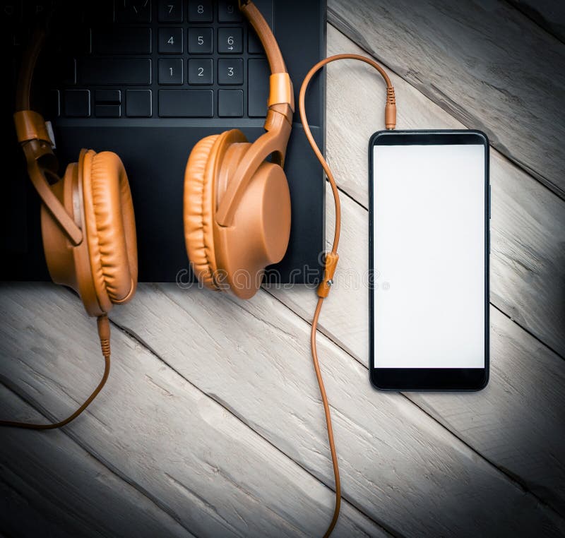 Top view of musical headphones on pc keyboard. Audio music headphones with a laptop and with a smartphone with a white display for royalty free stock image