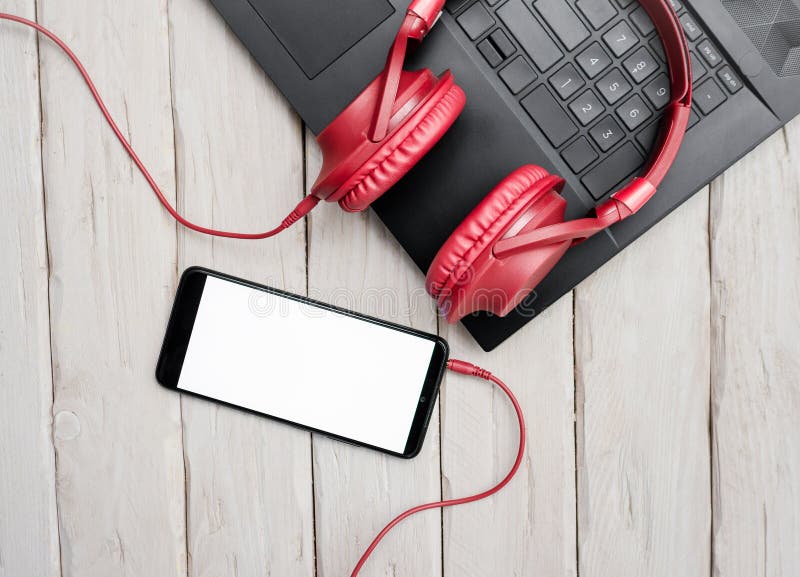 Top view musical red overhead headphones on pc keyboard. Audio music headphones with laptop and with smartphone with white display royalty free stock images