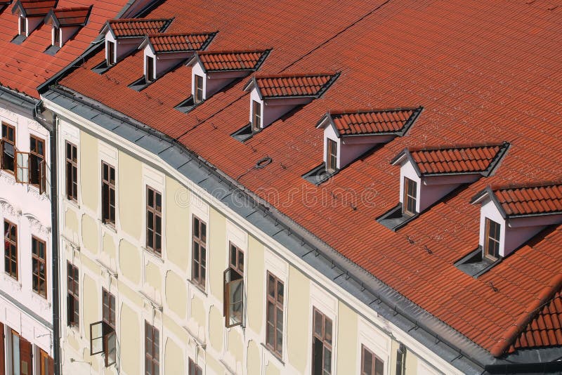 Top view of old building with red roof and windows on the roof. European city