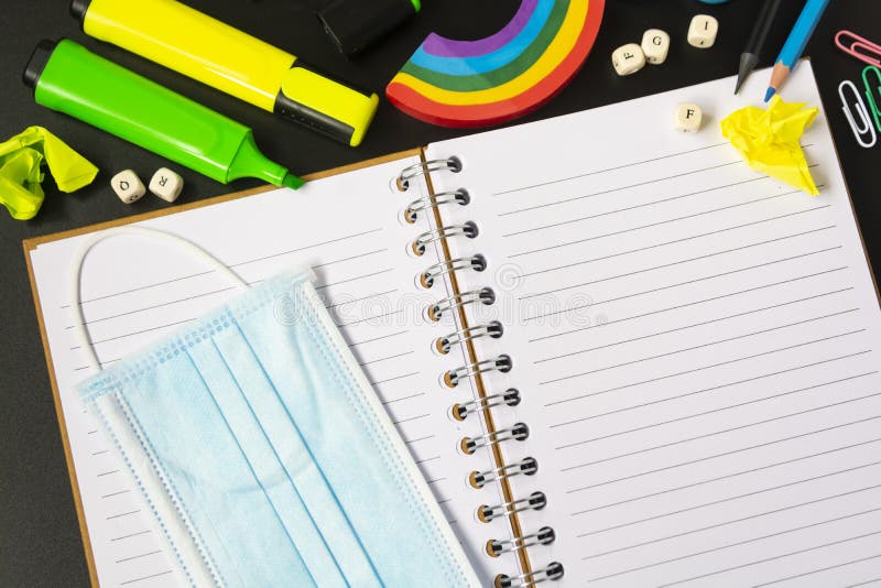 Top view of open notebook with face mask, colorful pencils, rainbow eraser, notebook, sticky notes. Flat lay. stock photos