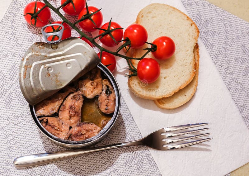 Top View of an Open Tin Can of Fish, with a Fork, Bread and Cherry