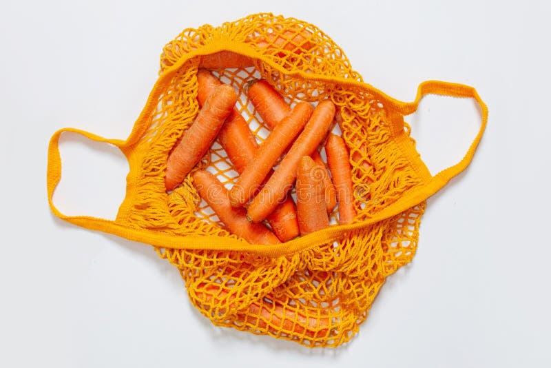 Top View of an Orange Mesh Grocery Bag with Carrots Isolated on a White