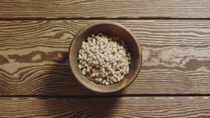 TOP VIEW: Peeled pine nuts fill wooden cup on a wooden table royalty free stock photo