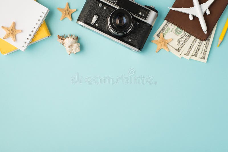 Top view photo of yellow notebooks camera pencil plane model on passport cover with dollars seashell and starfishes on isolated