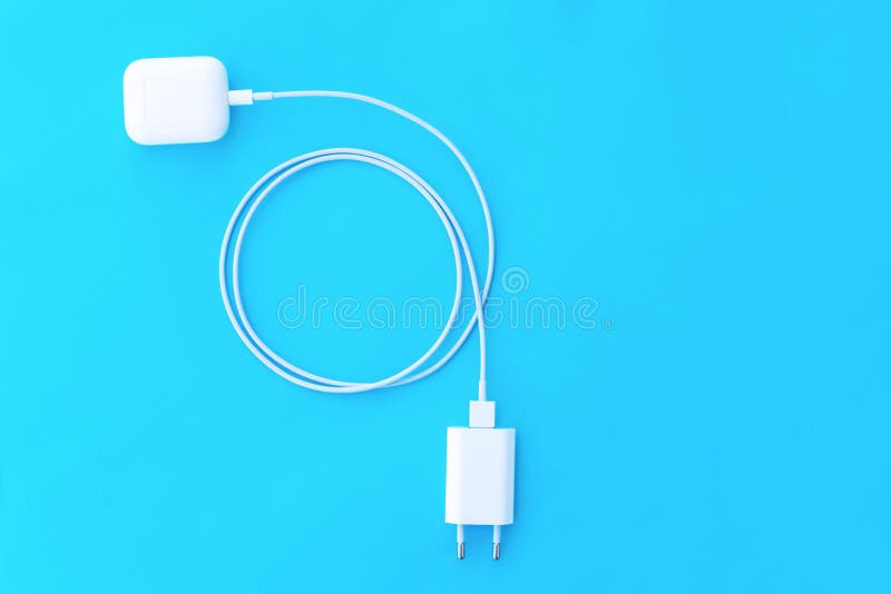 Top view plastic white wireless headphones for smartphone, charging case, Lighning USB, adapter on a pastel blue background. Copy stock photos Top view plastic white wireless headphones for smartphone, charging case, Lighning USB, adapter on a pastel blue background. Copy stock photos