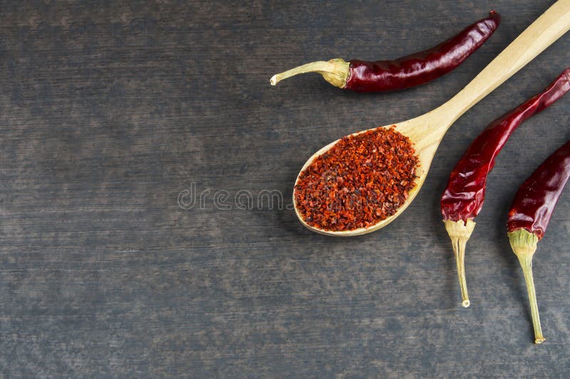 Top view red dried crushed hot chili peppers and chili flakes or powder in wooden spoon and bowl