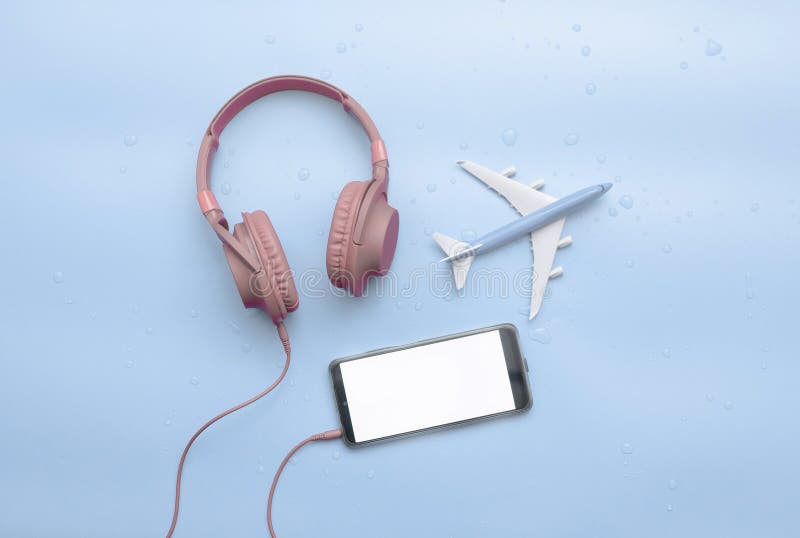 Top view, red musical headphones in water drops, with airplane travel concept, copy space. Headphones on a blue background on a royalty free stock photography