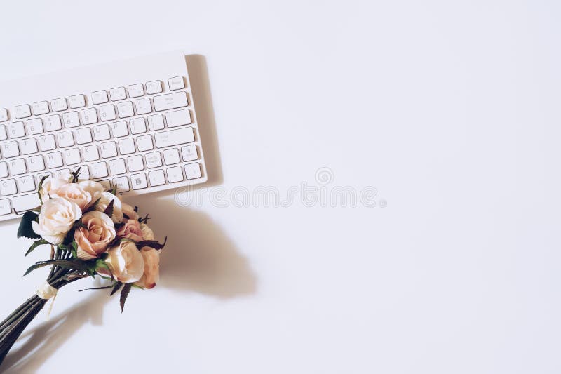 Top view of rose flower on the wireless keyboard on white background. Women`s office desk, female workspace. Valentines ` day