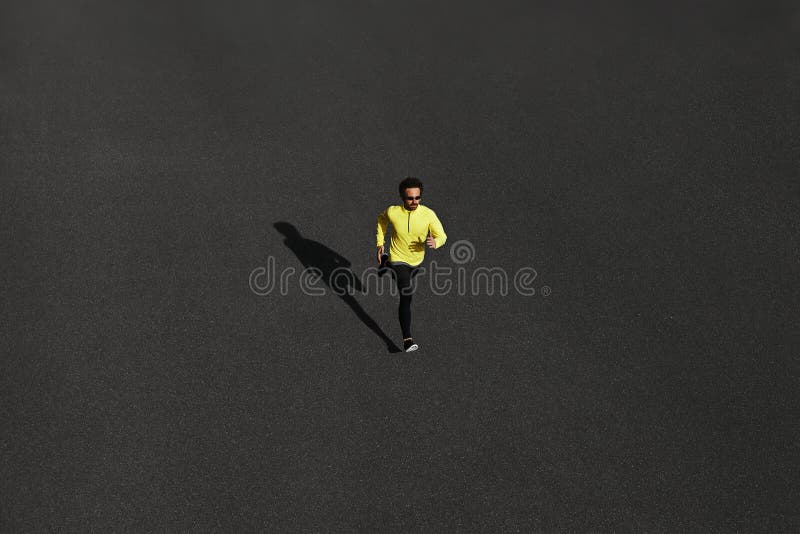 Top view runner man running sprinting for success on run at black road in yellow sportswear. Muscular fit sport model sprinter ex stock photo Top view runner man running sprinting for success on run at black road in yellow sportswear. Muscular fit sport model sprinter ex stock photo