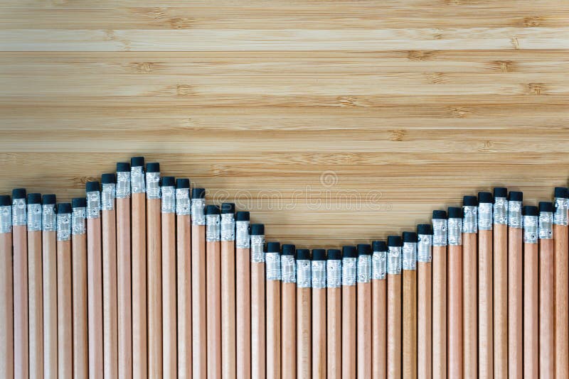 Top view of several pencils located in row on wooden table. Sharp pens laying in chaotic order. Tool for drawings on paper.