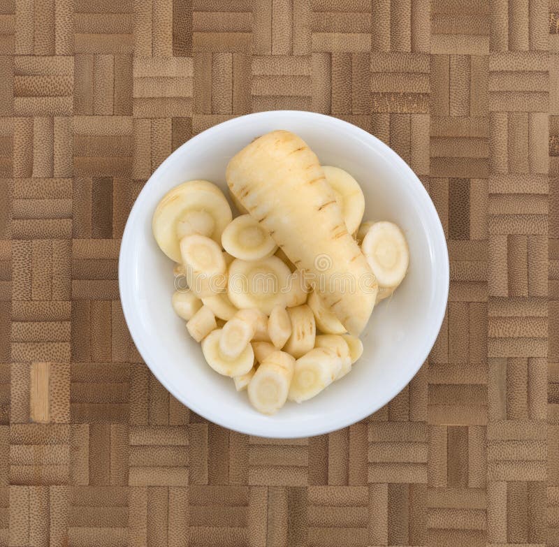 Slices of parsnip in a bowl on a wood cutting board royalty free stock image