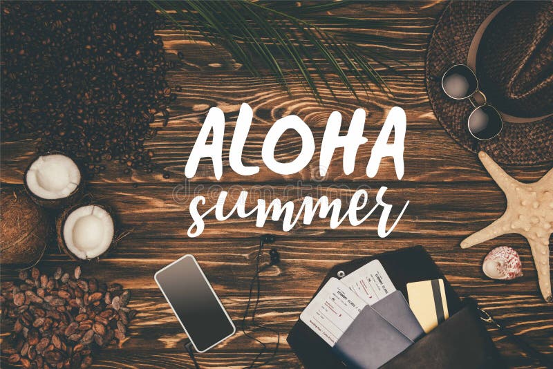 Top view smartphone and flight tickets surrounded with various tropical travel attributes on wooden surface with Aloha stock images