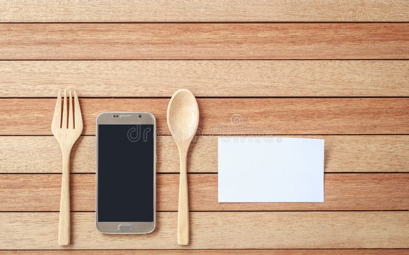Top view smartphone, spoon and fork on wooden plank background stock photo