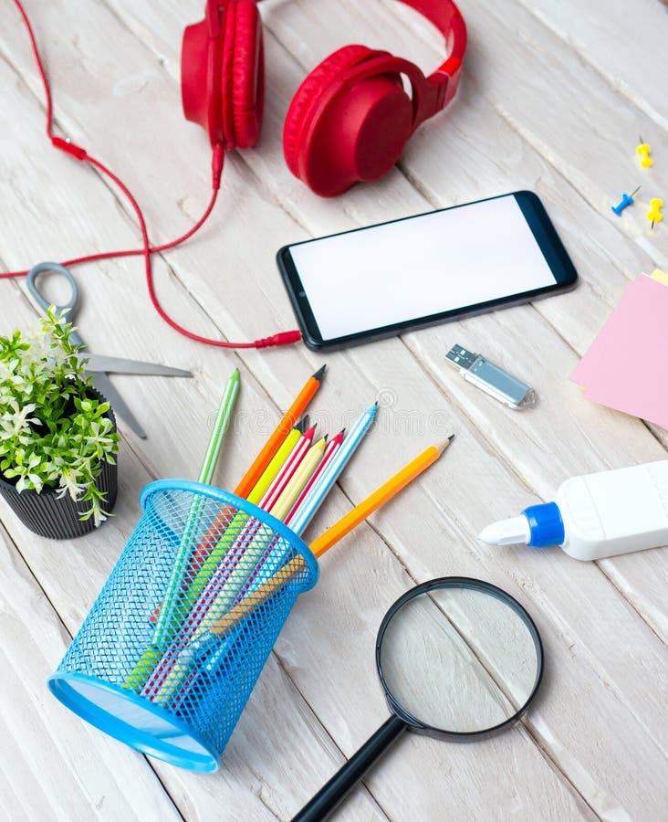 Top view Smartphone with white display for text, headphones on wooden table with pencils with notepad and pen. Home Office. Office royalty free stock photography