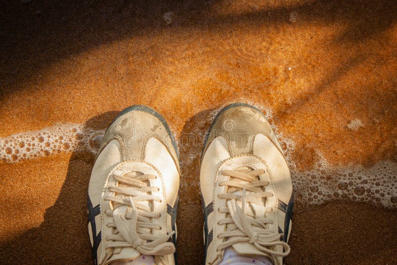 Top view sneakers on sand beach surrounded with clear sea water and shadow of tree in vintage style. royalty free stock images Top view sneakers on sand beach surrounded with clear sea water and shadow of tree in vintage style. royalty free stock images