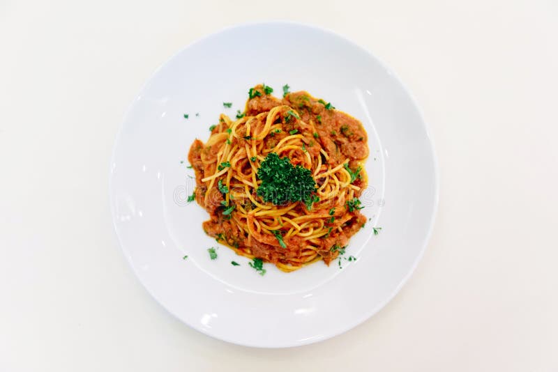 Top view of Spaghetti Sauce with Ground Beef in white bowl on white tablecloth with silver spoon.