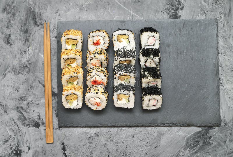 Sushi rolls on grey stone background.