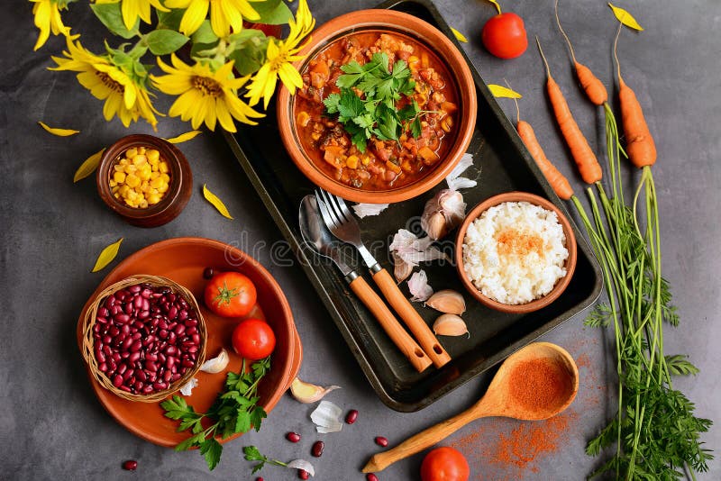 Top view of a table with dishes with beans, corn, tomatoes, parsley, garlic. Kitchen still life with sunflowers