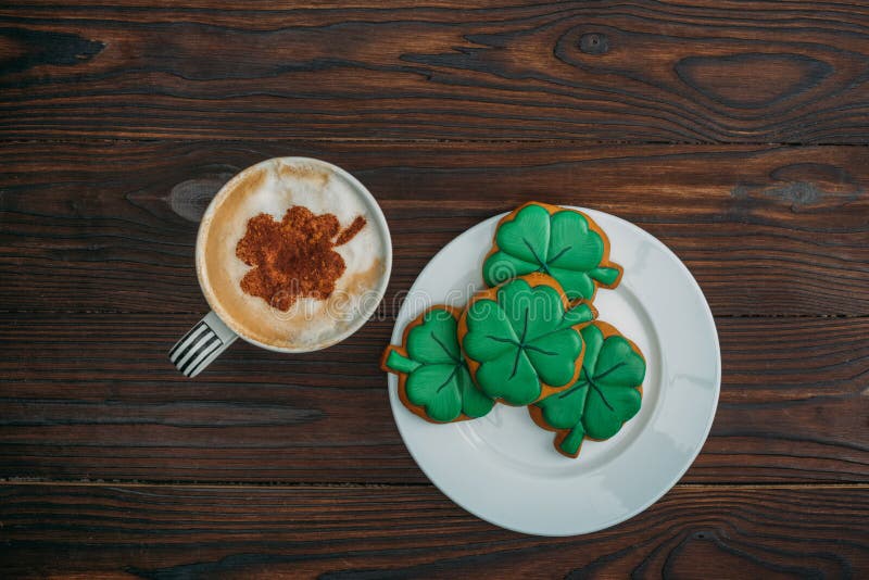 top view of tasty cappuccino and cookies in shape of clovers stock photo