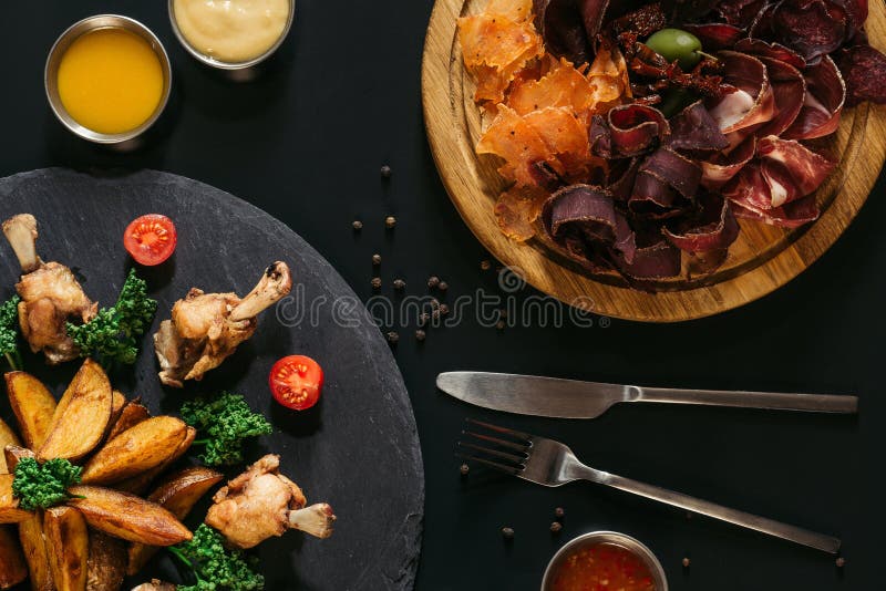 top view of tasty roasted potatoes with chicken and gourmet assorted meat on black royalty free stock photo